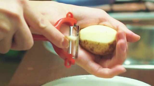 Women's hands peel potatoes