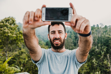 .Young and smiling man doing some tourism in the north of Bali, Indonesia. Making stops in the middle of the jungle and enjoying every moment and taking some pictures. Travel photography. Lifestyle.