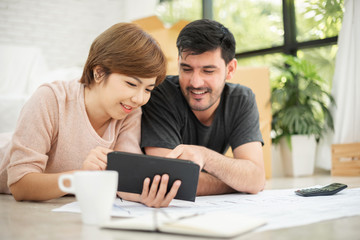 Couple with digital tablet and blueprints planning their new moving house.