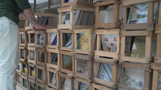 Male hands choosing  hand made and hand painted ceramic tiles from open wood crates