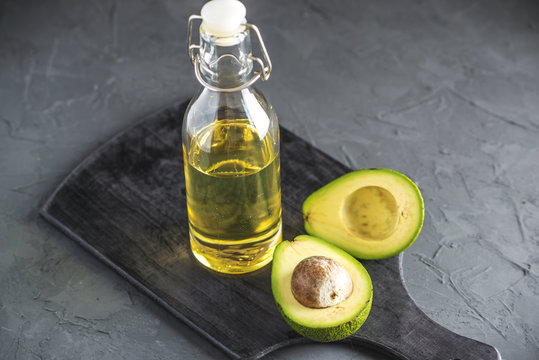 Avocado fruit and oil in glass bottle on dark background. Concept organic eco products for food and cosmetic procedures