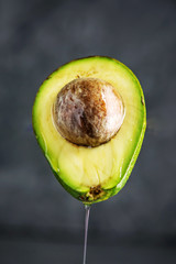 Oil flowing from the avocado fruit cut in half on dark background. Organic eco products for food and cosmetic procedures