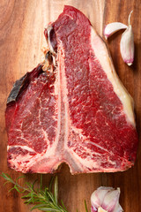 Meat for a barbecue. One raw piece of beef meat on the bone. steak t bone, salt, spices on a wooden...