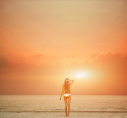 Fototapeta na wymiar beautiful sexual young woman stands on the beach against the sea and sky. happy woman enjoying summer vacation