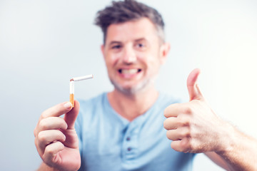 Smiling young man holding a broken cigarette