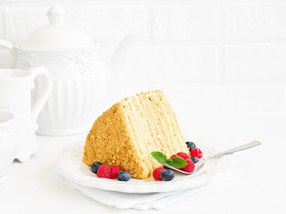 A piece of multi-layered honey cake with fresh berries. Selective focus