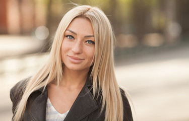 Portrait of the young beautiful smiling woman outdoors enjoying summer sun. Young woman outdoors portrait. Soft sunny colors. Beautiful blonde woman outdoor