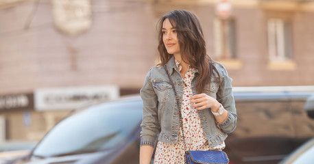 Young beautiful stylish girl walking and posing in short summer dress in city. Outdoor summer portrait of young woman