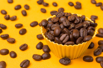 yellow cup with a drink of coffee with foam on a yellow background, next coffee beans