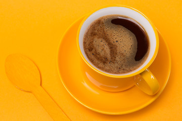 yellow cup with a drink of coffee with foam on a yellow background, next coffee beans