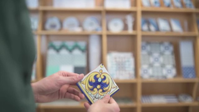 Male hands inspecting a small ceramic tile