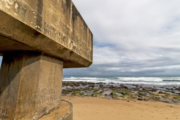 Concrete  Pipeline Extending onto  Beach and Rocky Coastal Seascape