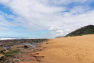 Rocky Beach Waves and Ocean Against Blue Cloudy Skyline