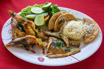 A variety of seafood grill on a large platter. King prawns, crab langoustines and fish with torillas, cheese and lime.