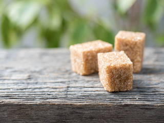 Brown cane sugar on wooden background. Green tree with leaves
