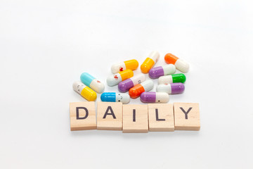 word daily with colorful pill on white background