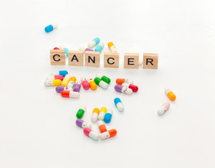 word CANCER with colorful pill on white background