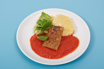 Tempeh with tomato sauce and dumplings on a blue