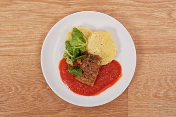 Tempeh with tomato sauce and dumplings on a table