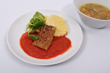 Tempeh with tomato sauce and dumplings on a white