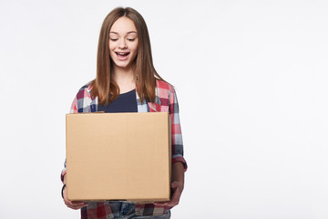Happy excited woman holding cardboard box with expression of surprise, over white background