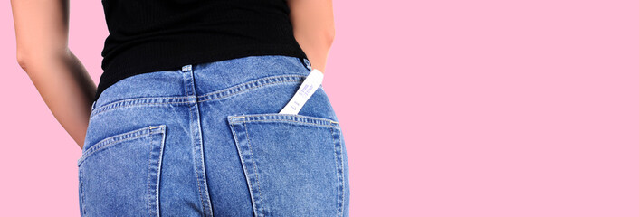 Woman with pregnancy test in pocket jeans