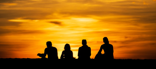 Groups of silhouette people Do activity on the beach on the Sunset  and show the posture during a vacation at the tropical beach in travel and holiday concept.