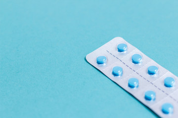 Blue pills in blister on blue background
