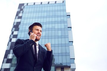 Businessman speaks on the phone outdoors. Business.