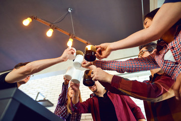 Friends raised their hands upwards with cup inside the room.