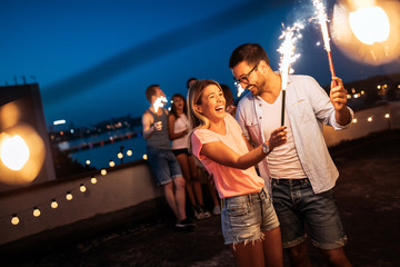 Friends enjoying rooftop party with sparklers