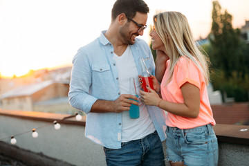 Happy young couple drinking cocktail on rooftop
