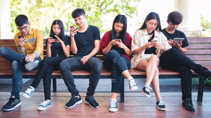 Fototapeta premium Group adult hipsters friends sitting sofa using hands modern smartphone tablet, Business startup friendship teamwork concept, People working together project