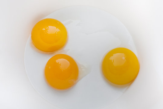 три сырых желтка от куриных яиц на дне белой миски
