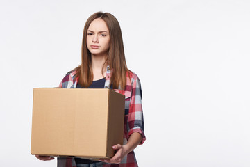 Discontent woman holding cardboard box frowning brows, over white background