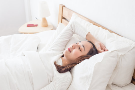 Asian Woman have a headache after wake up lying on bed feeling so sick in the morning,Healthcare Concept