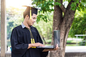 Attractive Asian graduate man using laptop for find a job feeling so happiness and...