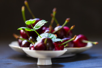 Cherry on a dark background with a sprig of mint. Food photography.
