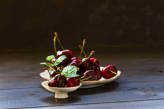 Cherry on a dark background with a sprig of mint. Food photography.
