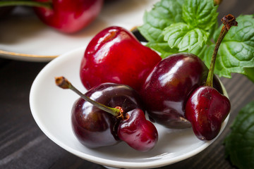 Cherry on a dark background with a sprig of mint. Food photography.