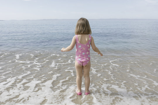 Back view of little girl standing at seafront
