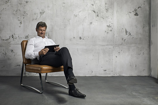 Mature man using digital tablet in front of concrete wall