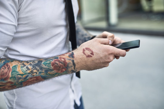 Young businessman with tattooed face using smartphone