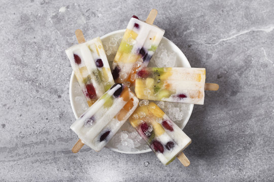 Homemade fruits and yogurt ice lollies on marble