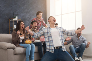 Very excited friends watching football match at home