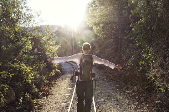 Greece, Pilion, Milies, back view of man with backpack balancing along rails of Narrow Gauge Railway