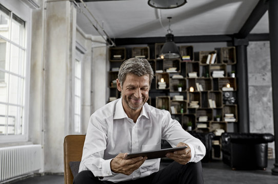 Smiling mature man using digital tablet in loft