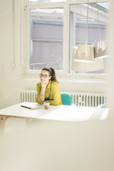 Fototapeta na wymiar Portrait of happy freelancer sitting at desk in studio
