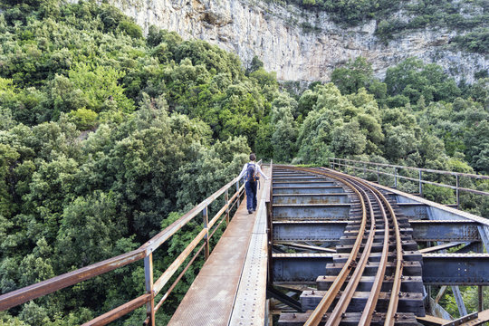 Greece, Pilion, Milies, back view of man walking on bridge along rails of Narrow Gauge Railway