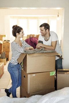 Young couple moving house, unpacking cardboard boxes